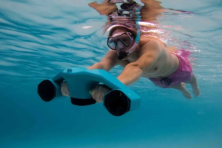 Snorkeler holding a battery-powered sea scooter above a reef on a Bonaire snorkeling tour near Kralendijk